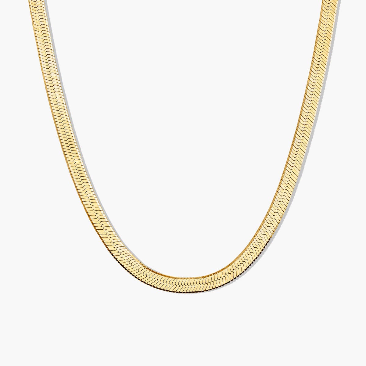 The Mejuri Bold Herringbone Chain necklace in gold vermeil, laid in a loose curve.